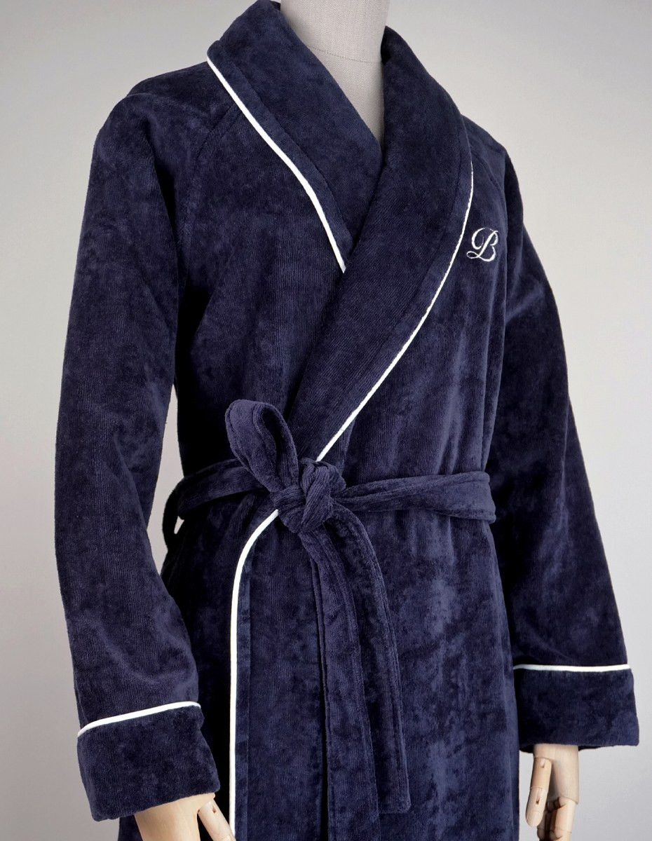 balmuir_portofino_robe_darknavy_closeup_web Der Bademantel Portofino besteht aus 100 % Baumwolle. Das Bademantel-Design zeichnet sich durch einen markanten Schalkragen und einen passenden Gürtel aus. Es ist mit Paspeldetails am Schalkragen und an den Ärmeln sowie einem raffiniert gestickten Markenlogo versehen. Unsere Portofino-Bademäntel werden in Portugal in perfekter Handarbeit gefertigt.
