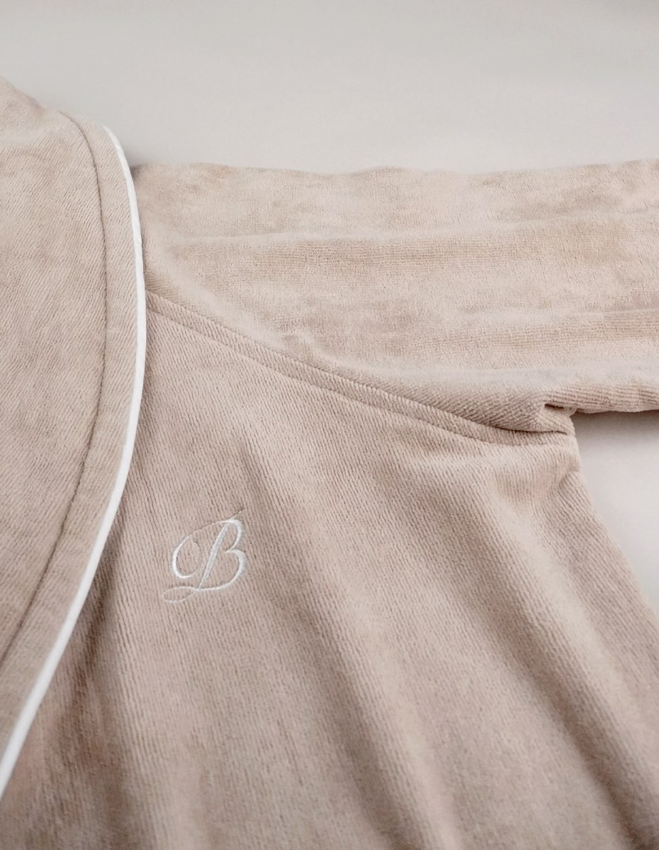 balmuir_portofino_robe_darktaupe_closeup_2_web Der Bademantel Portofino besteht aus 100 % Baumwolle. Das Bademantel-Design zeichnet sich durch einen markanten Schalkragen und einen passenden Gürtel aus. Es ist mit Paspeldetails am Schalkragen und an den Ärmeln sowie einem raffiniert gestickten Markenlogo versehen. Unsere Portofino-Bademäntel werden in Portugal in perfekter Handarbeit gefertigt.