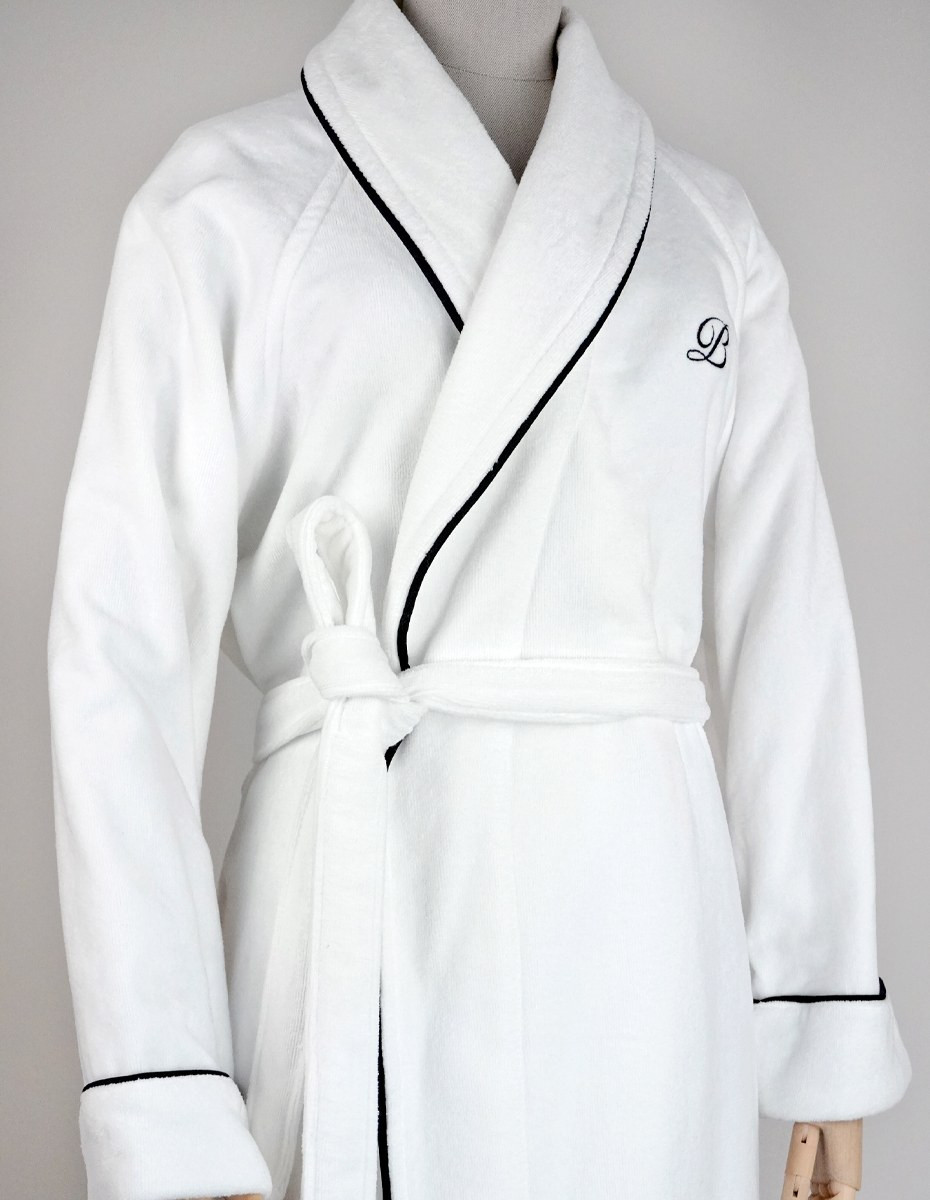 balmuir_portofino_robe_white_closeup_web Der Bademantel Portofino besteht aus 100 % Baumwolle. Das Bademantel-Design zeichnet sich durch einen markanten Schalkragen und einen passenden Gürtel aus. Es ist mit Paspeldetails am Schalkragen und an den Ärmeln sowie einem raffiniert gestickten Markenlogo versehen. Unsere Portofino-Bademäntel werden in Portugal in perfekter Handarbeit gefertigt.